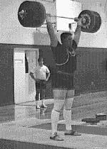 As soon as the bar leaves the shoulders, the lifter drives him or herself under the bar by splitting his or her legs apart. The weight is held overhead with straight arms locked out at the elbows.