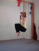 4 Sit directly under the trainer with legs crossed with arms stretched overhead and hands in