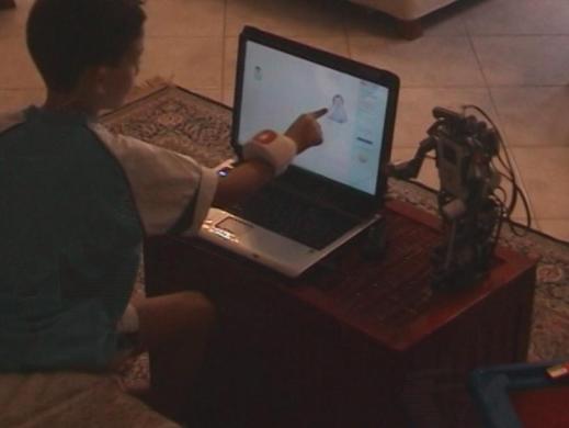 Figure 6. An example of kid s interaction with NOESIS and NOE-robot. Note the Exmocare BT2 Watch in kid s right hand, which does not prevent him to interact.