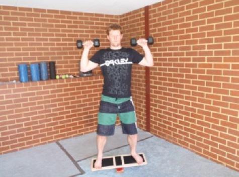 Functional Strength Workout B Dynamic Warm-up Balance Board Shoulder Press Stand on a balance board holding a light