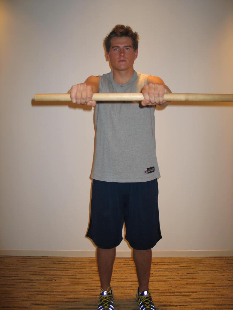 flexed, left hand is on the mid shaft on the wand and pulls right shoulder across the body