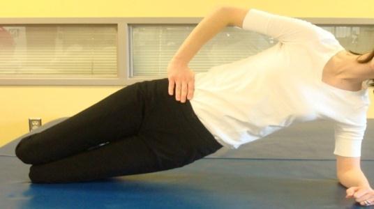 Side Plank Hold Patient assumes the side plank position, with forearm support directly below the shoulder of the bottom arm, and foot support with feet stacked one on top of the other.