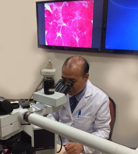 Dr. Qiang Liu, surgical pathologist, examines a liver tissue sample. Dr.