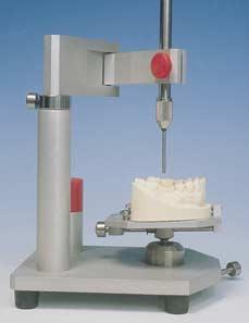 The surveyor allows a vertical arm to be brought into contact with the teeth and ridges of the dental cast, thus