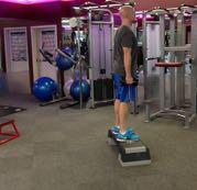 DB Reverse Lunge from a Deficit Stand upright on a small step or platform holding a pair of dumbbells.