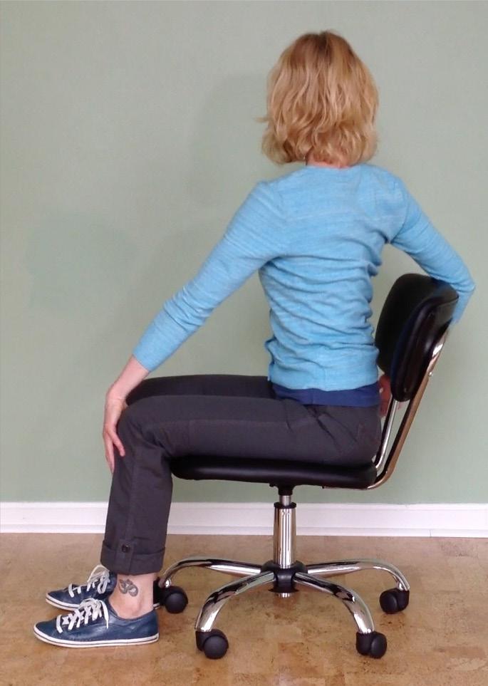 Look to your left, and drape your back arm over the back of your chair, letting the inside of your arm curve slightly around the chair back and act as a brace.
