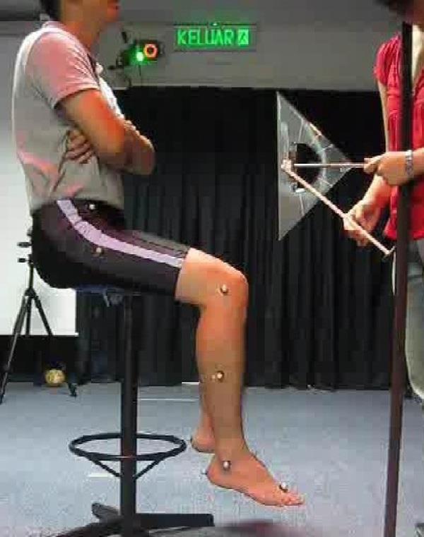 Fig. 1. Experimental setup for reflex assessment tests. The subject sits on a high stool with both feet not touching the ground.
