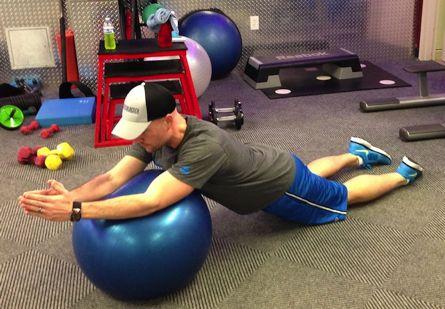 Brace your abs and slowly lean forward and roll your hands over the ball while the