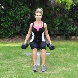 DB Seated Hang Clean Preparation: Position yourself on the edge of a bench grasping two dumbbells by your side, palms facing in.