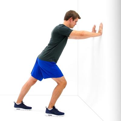 Lean forward towards the wall and support yourself with your arms as you allow your front knee to bend until a gentle stretch is felt along the back of your leg that is most