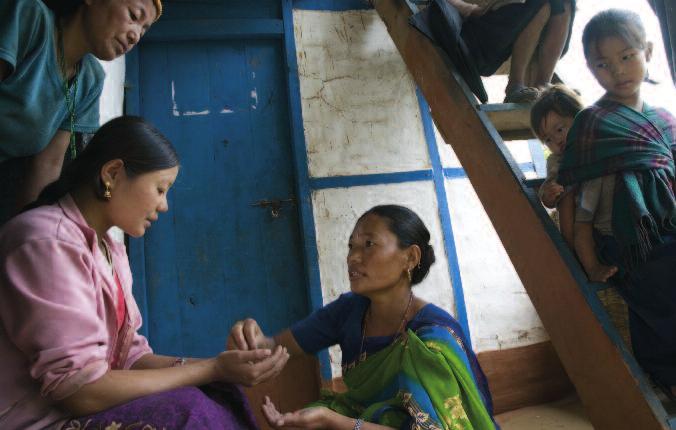 A community health volunteer, gives Sushmita Sumbhamphe, who is nine months pregnant, vitamin A, iron and folic acid supplements, during a home visit in the remote, mountainous Eastern Region of