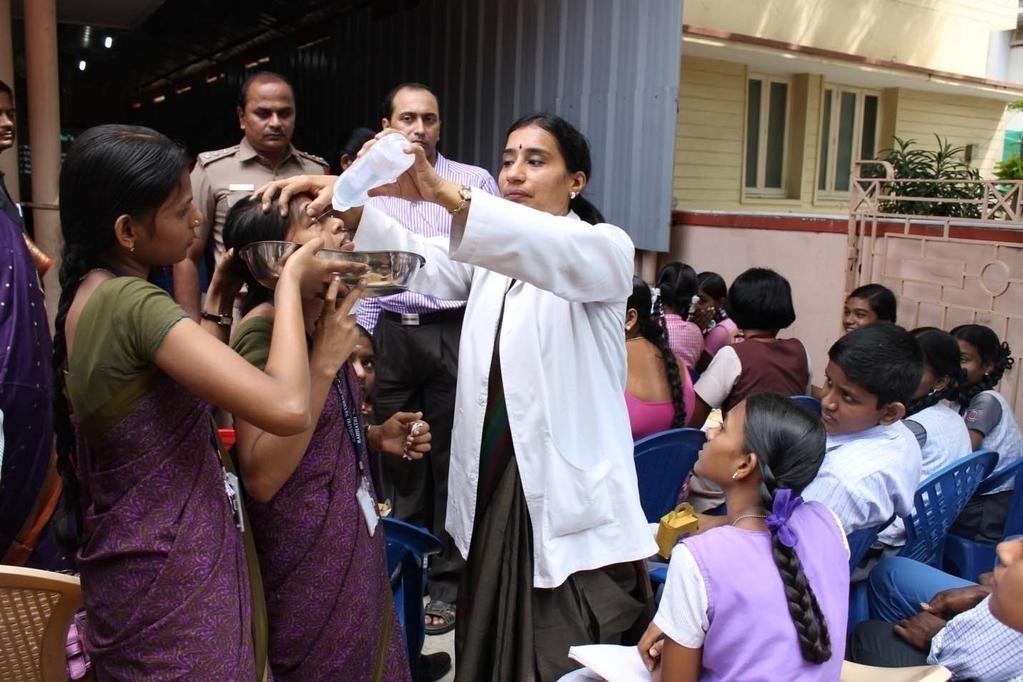 Dr. Vasumathy demonstrating the technique of washing the eyes as a first aid in cracker injuries as school students and teachers look on.