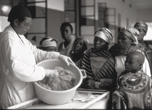 UNICEF/HQ99-0452/PIROZZI At a hospital in Rwanda, a nurse demonstrates how to treat a mosquito net with insecticide to prevent malaria.