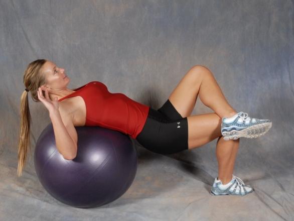33 Leg Cross Crunch - Lie across a fitness ball with the top of your hips and low back in contact with the ball.