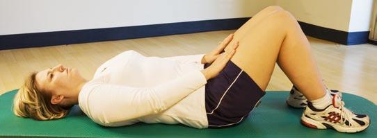 Core: Abdominal Curl-Up Lie flat on your back with your knees slightly bent and arms resting on your thighs.