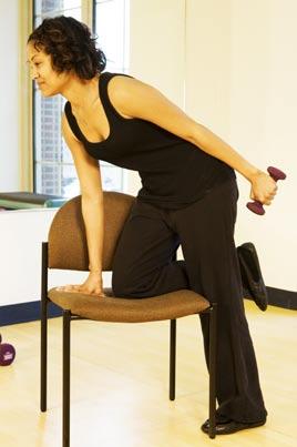 With the dumbbell in the left hand, bend forward slightly, keeping your back flat and stomach tight.