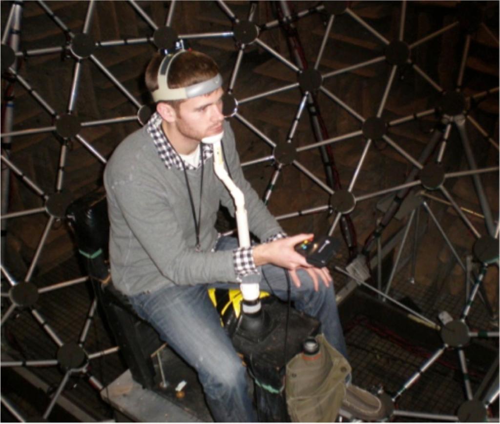 Figure 2.2: Subject seated on the bench mounted to the adjustable platform in the center of the geodesic sphere in the Auditory Localization Facility.