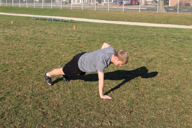 While maintaining the plank position, bend your right elbow and lift your right hand off the ground. 3.