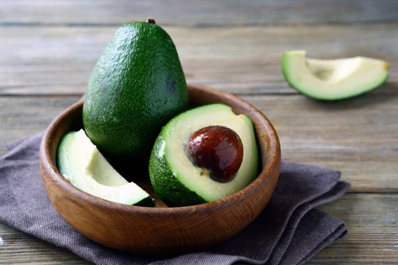They are in the shape of a pear and the outer leather skin in green or black in color. The inside of the avocado is green with a large brown seed.