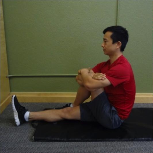 Seated Crossover Glute Stretch Instructions: Sit on a mat, cross one leg over another keeping the bottom leg straight.