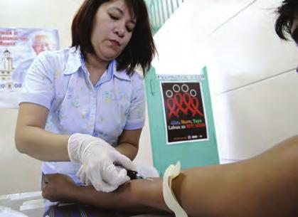 COMBATING COMMUNICABLE DISEASES A medical technician draws blood for HIV screening in Manila.