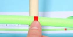 Place the mini toober on top of and perpendicular to the bottom of the dowel, positioning the first red band on top of the dowel. (See photo.) 12.