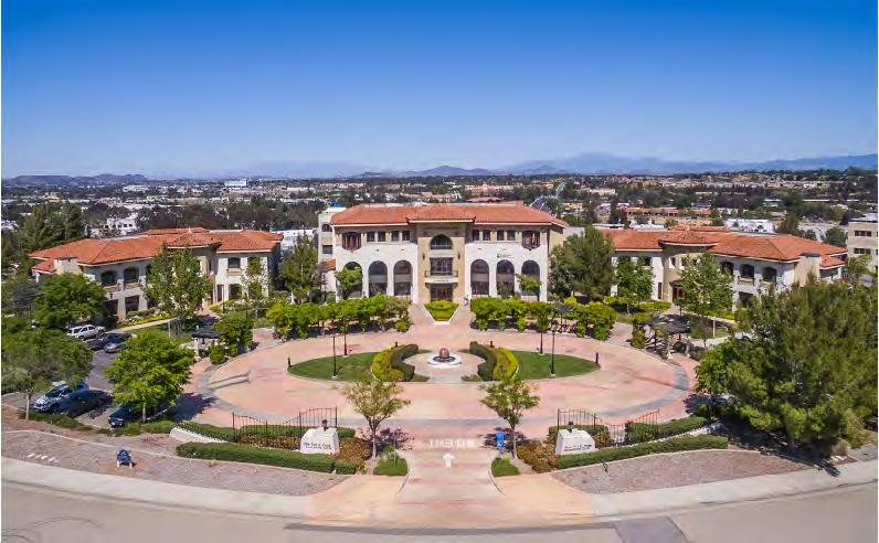 Serene park-like campus setting with lush landscaping, trellis-covered pathways, a beautiful water feature in a grand entry circular driveway, classic architecture and
