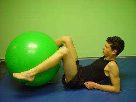 LYING SIDE CRUNCH: Lie on back with ball under bent