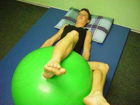 LUMBAR ROTATIONS: Lie on back with ball under bent legs,