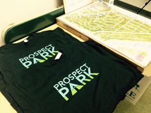 Prospect Park T-Shirts Available These shirts are 100% cotton and printed with the words "PROSPECT PARK". Within the design there is a scene of sky and trees.