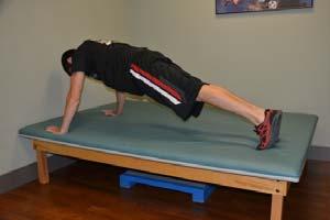 Keep your back straight and do not let your stomach sag. Action: Slowly bend your elbows, lowering your trunk and thighs toward the surface of the mat.