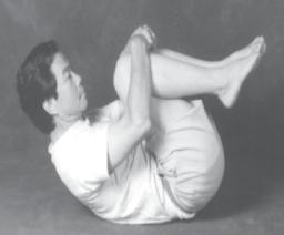 Relax legs - raise sacrum and thoracics: Raise both legs, clasping your hands over your knees.