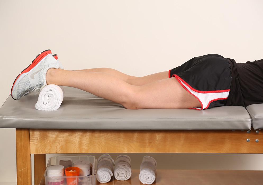 23 Prone terminal knee extension Lie on your stomach, with your legs and feet together. Keep your hips flat on the table. Place a towel under the ankle on the surgery leg.