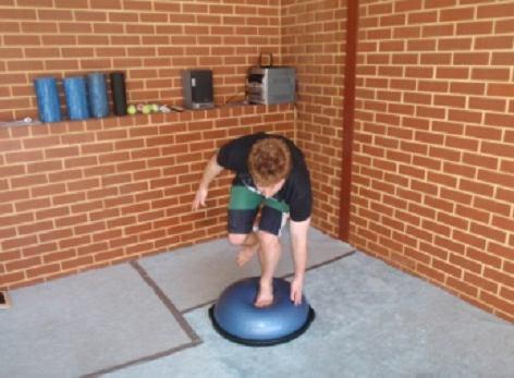 Bend your knee and bent down to touch one hand on the side of the BOSU.