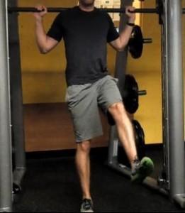 Single leg squat Begin with a bar on a rack at shoulder height.