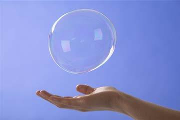 large soap bubble floats down to an outstretched hand.