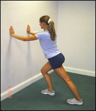 Adopt a split stance in front of a wall with both feet facing forward Hands contact the wall at shoulder height with