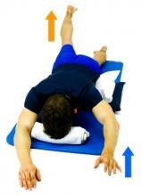Prone Alternating Arm and Leg Lie face down on a comfortable surface with a pillow under your stomach and small rolled towel under your forehead.