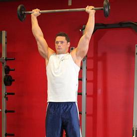 Slightly bend the knees and place the barbell on your collar bone. Lift the barbell up keeping it lying on your chest. Take a step back and position your feet shoulder width apart from each other. 3.