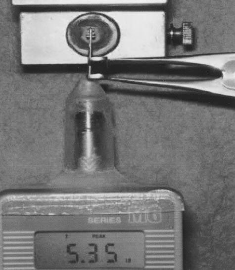 A shear debonding force is recorded as the cross-member moves away from the gauge and causes bond failure at the bracket-enamel interface. Note the reading of 5.35 lb displayed on the gauge.