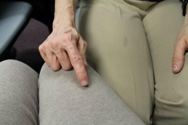 A hand in a resting fisted position on the knee of the partner.