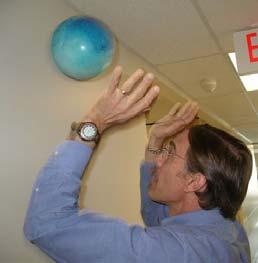 Stand facing the wall and use two hands to bounce a ball on the