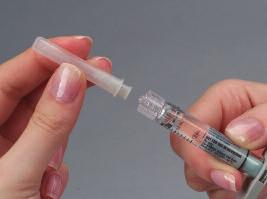 With the needle cover still on, in the partially opened paper packaging, twist the new 27-gauge needle onto the syringe until