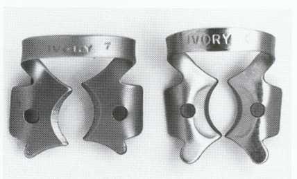 Fig. 5-32 Basic set of ivory-winged rubber dam clamps: top, no. 9 butterfly clamp for anterior teeth; bottom (from left), no. 2 premolar clamp, no.