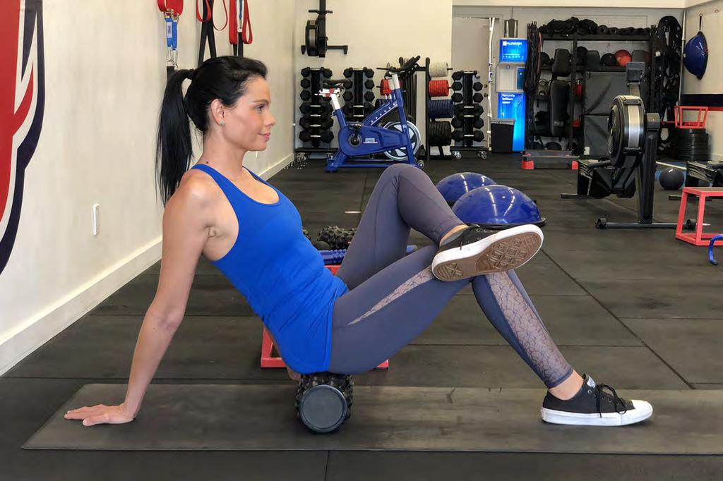 HIP TECHNIQUE: 1. While sitting on the foam roller on the floor, cross one leg over your knee as if you were sitting cross-legged in a chair.
