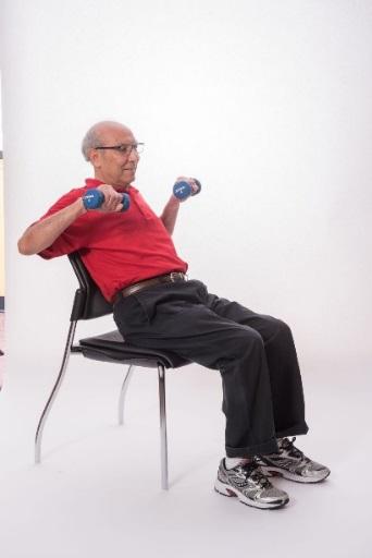 SEATED CHEST PRESS - DUMBBELLS Sit on a chair with your feet hip-distance apart. Bring dumbbells to the side of your chest. Straighten your arms.
