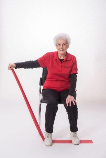 Stand with your feet hip-distance apart or sit in a chair with a straight back. Do not slouch in the chair. Place the band under your right foot. Hold one end of band in your right hand.