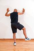 Flex one leg at the hip and the knee. Use your upper body to lean against the wall. Your back leg should be positioned straight ahead with a 30 bend at the knee.
