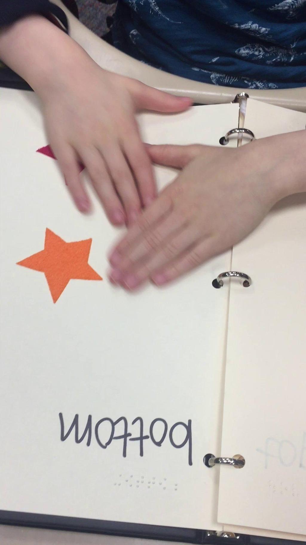 Visual Supports Classwork Video Description: Braille paper with bottom written in Braille and